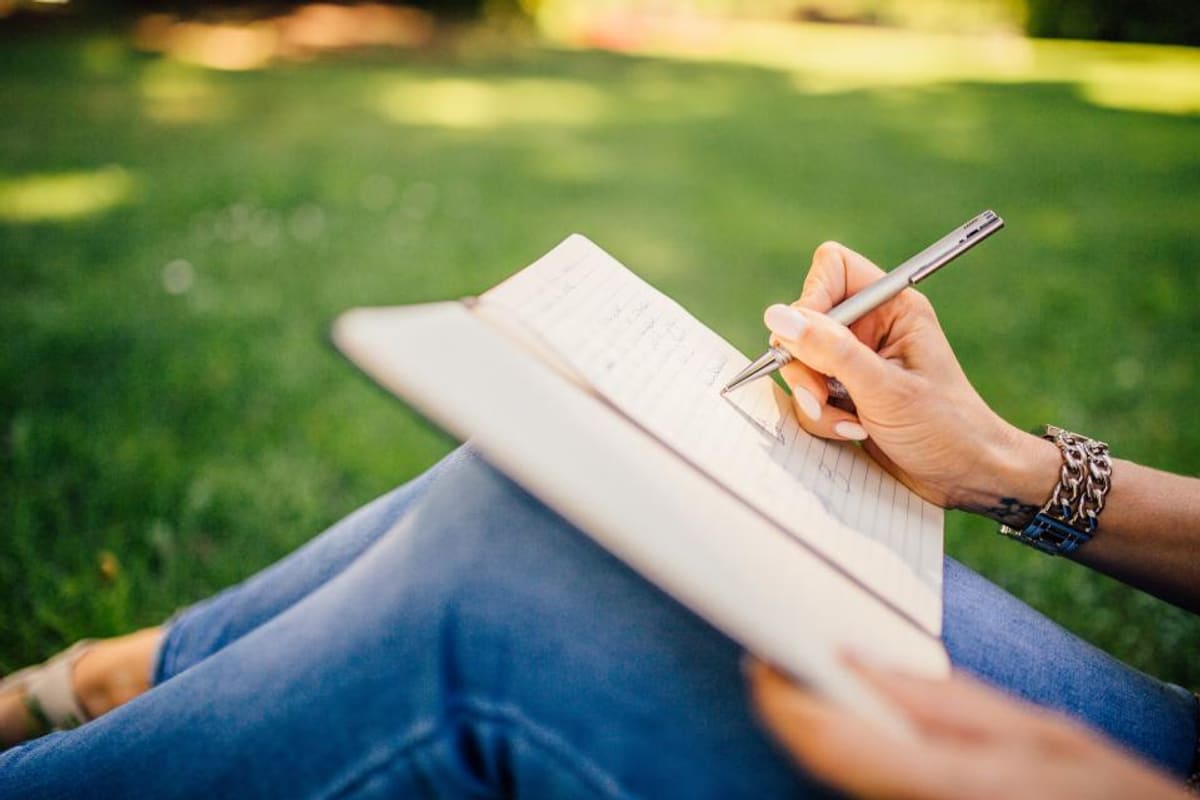 Person schreibt handschriftliche Notizen in ein aufgeschlagenes Heft