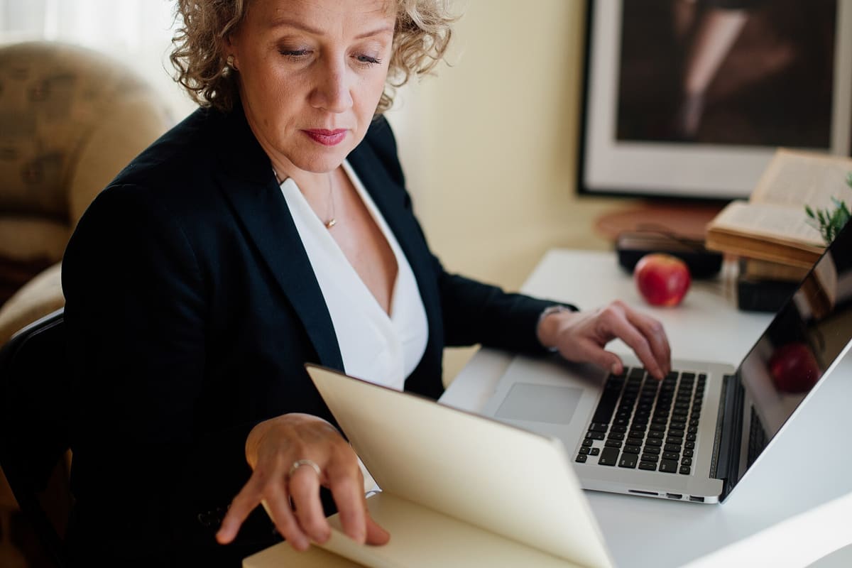 Person arbeitet an einem Schreibtisch mit Laptop und Dokumenten