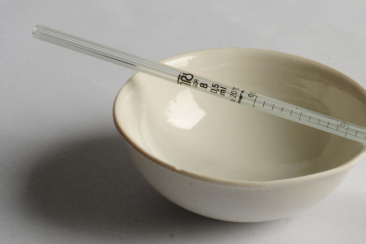 Glaspipette über einer Abdampfschale aus Porzellan