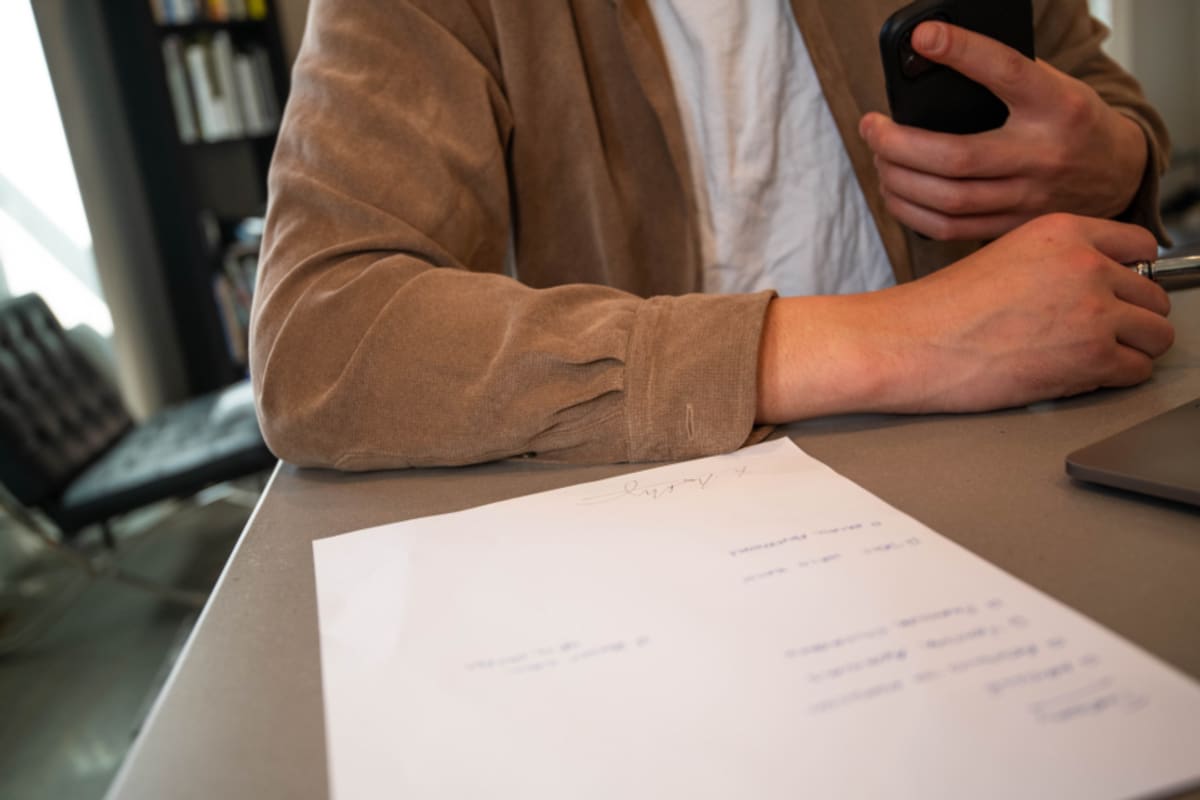 Person unterschreibt ein Dokument an einem Schreibtisch