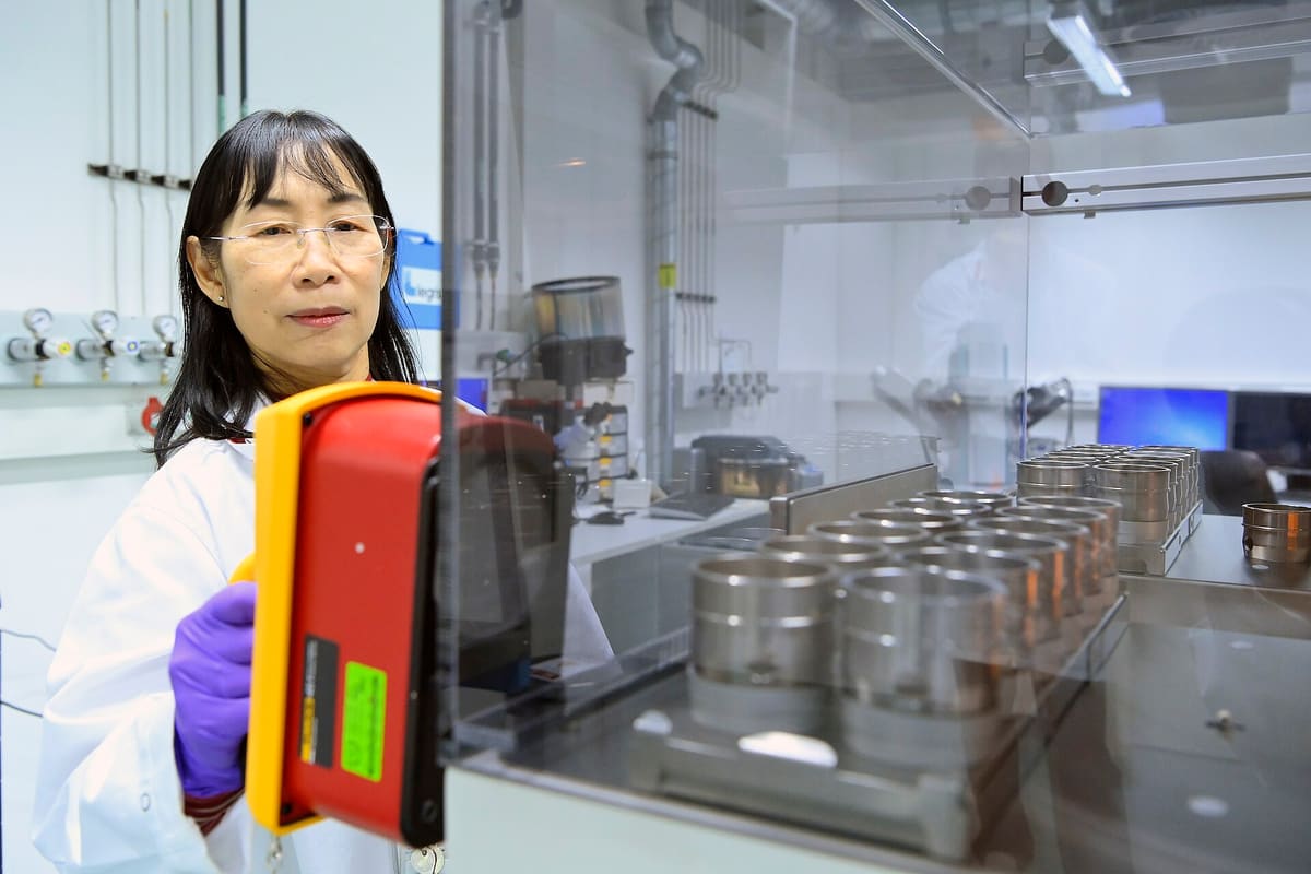 Wissenschaftlerin prüft Edelstahlbehälter mit einem Handmessgerät