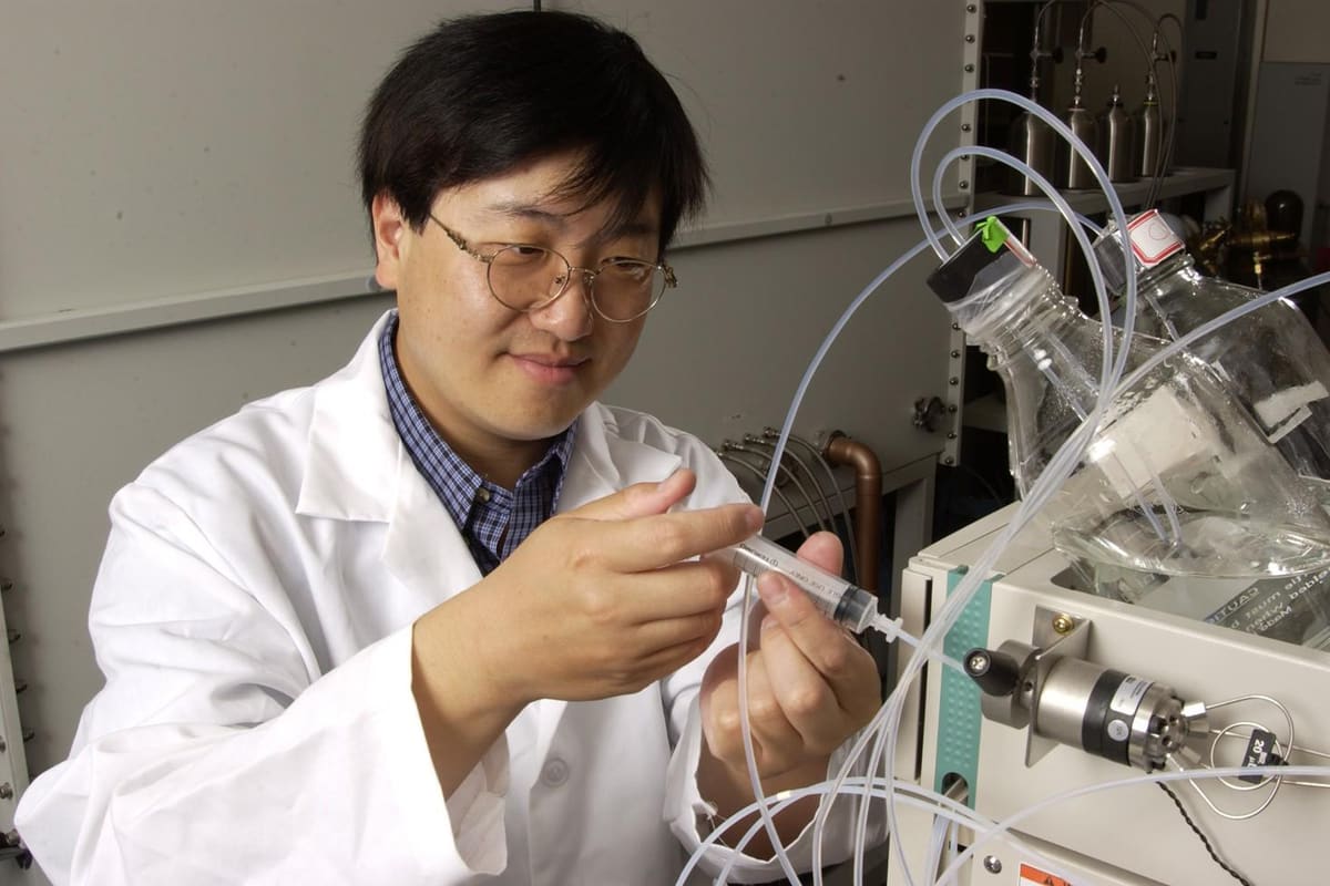 Chemiker gibt mit einer Spritze eine Probe in ein Analysengerät