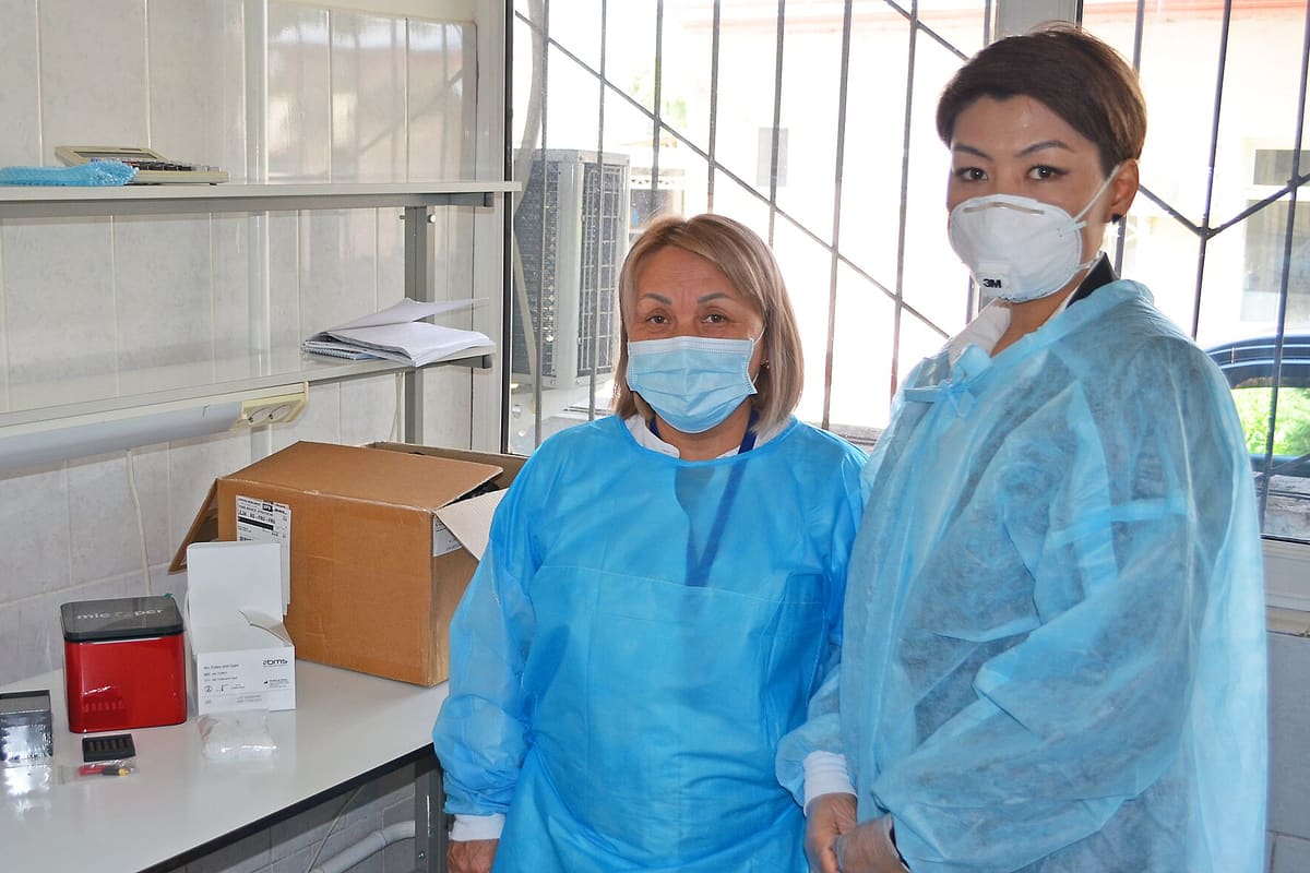 Zwei Wissenschaftlerinnen in Schutzkitteln und Masken in einem Probenraum
