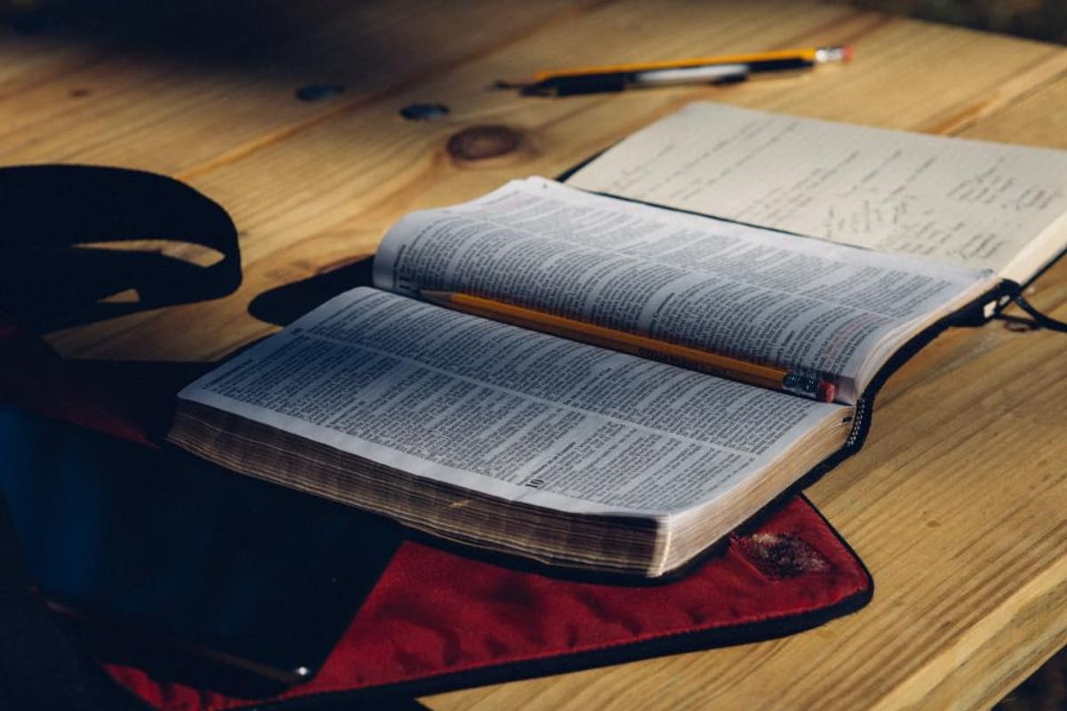 Zwei aufgeschlagene Notizbücher mit Stift auf einem Holztisch